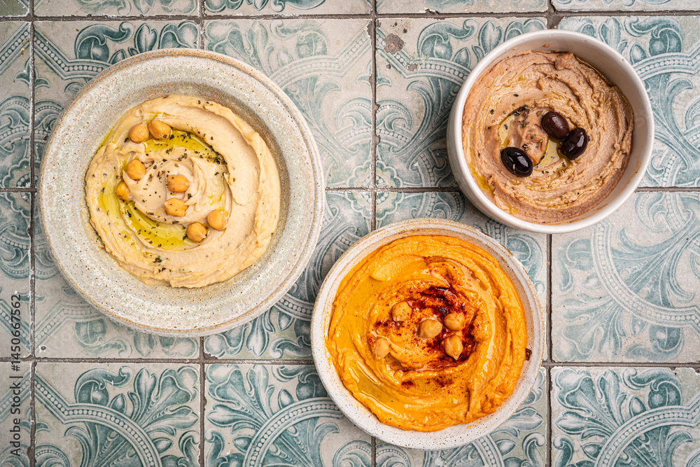 Various hummus dips in different colours. Hummus with dry crackers, top view. Vegan and traditional hummus as healthy and vegan snack.