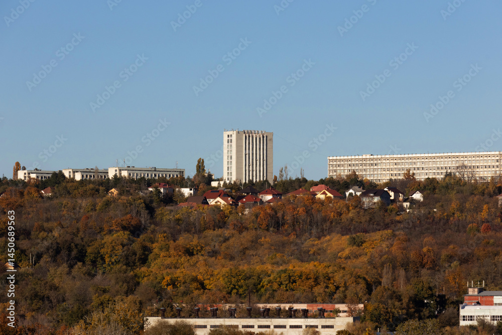 City buildings against the backdrop of an autumn forest
