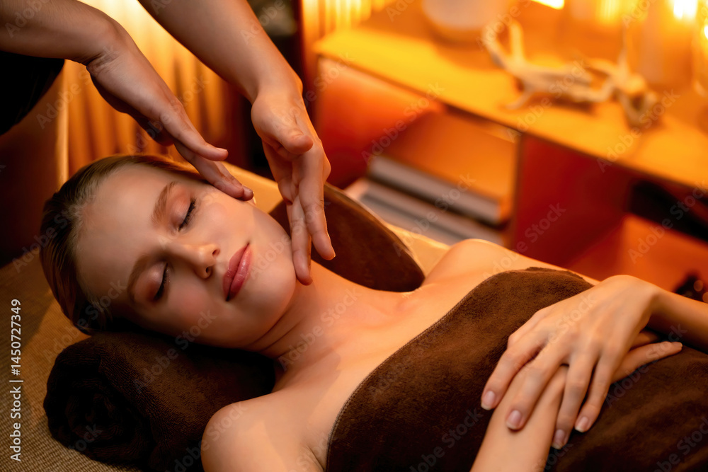 Fototapeta premium Caucasian woman enjoying relaxing anti-stress head massage and pampering facial beauty skin recreation leisure in warm candle lighting ambient salon spa in luxury resort or hotel. Quiescent