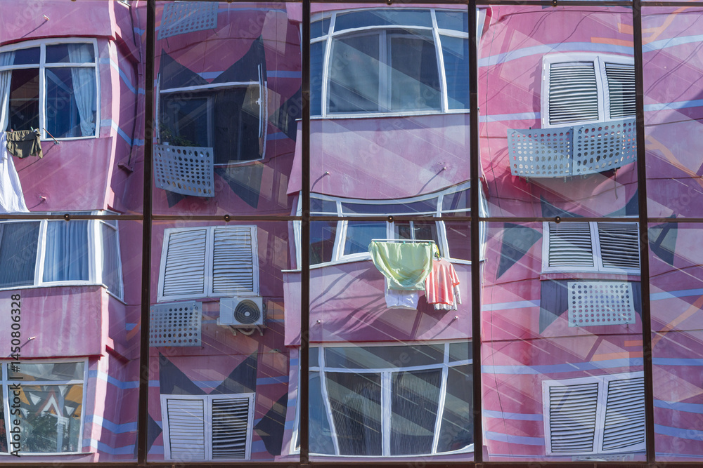 Pink apartment building reflected in windows.