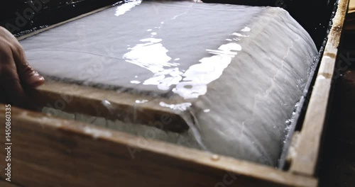 Super Slow Motion Close Up of Removing Sheets of Handmade Paper from Water Vat During Traditional Papermaking Process in Artisan Workshop with Natural Fibers and Wooden Tools at 1000 fps.