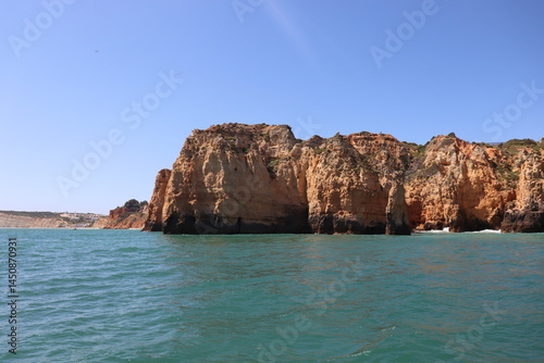 a photo of a rocky southern coast of portugal on a sunny summer day with ocean in the background