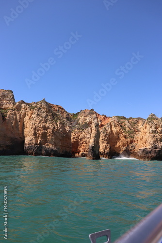 a photo of a rocky southern coast of portugal on a sunny summer day with ocean in the background