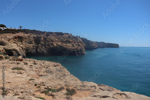 a photo of a rocky southern coast of portugal on a sunny summer day with ocean in the background