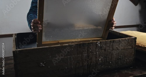 Super Slow Motion of Traditional Handmade Paper Making Process with Wooden Frame Being Lifted from Water Vat in Artisan Workshop Showing Wet Pulp Sheet Formation at 1000 fps.