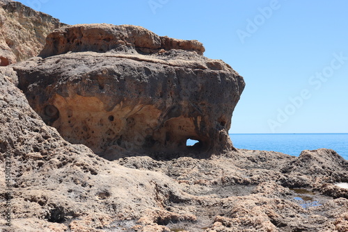 a photo of a rocky southern coast of portugal on a sunny summer day with ocean in the background