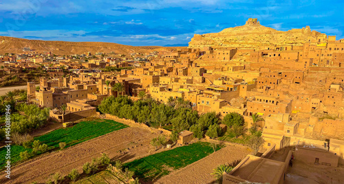 Φωτογραφία Golden light bathes the ancient clay architecture of Ouarzazate, Morocco’s desert jewel—where kasbahs rise from fertile valleys and history lingers in every sun-drenched wall