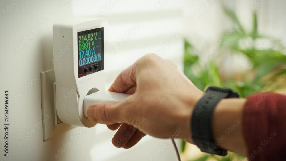 A person connects a digital energy monitor to an electrical outlet to measure power consumption. This activity takes place indoors during the daytime, showcasing energy usage awareness A person connects a digital energy monitor to an electrical outlet to measure power consumption. This activity takes place indoors during the daytime, showcasing energy usage awareness
