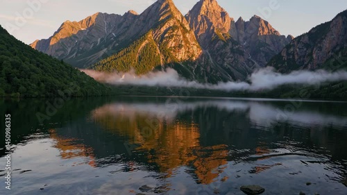 Serene Lake Reflecting Misty Mountains at Sunrise with Golden Light and Ripples
