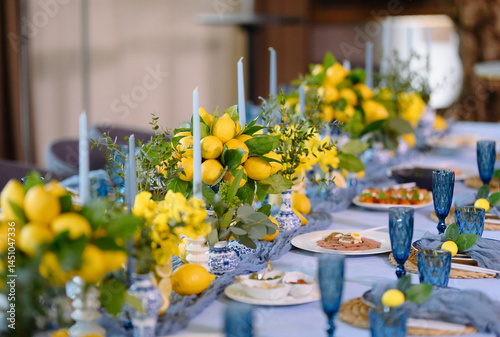 Beautiful lemon centerpiece with blue glassware and candles creates a fresh, festive table atmosphere.