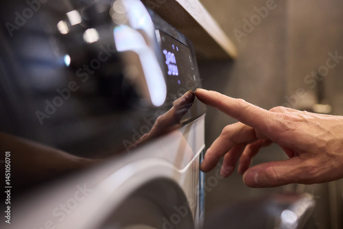 Obraz na płótnie Individual Interacting with a Modern Washing Machines Control Panel for Efficient Laundry Tasks w salonie