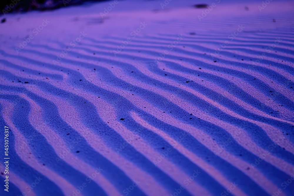 Fototapeta premium Close-up of rippled sand, purple hues. Detailed patterns of wind-formed dunes