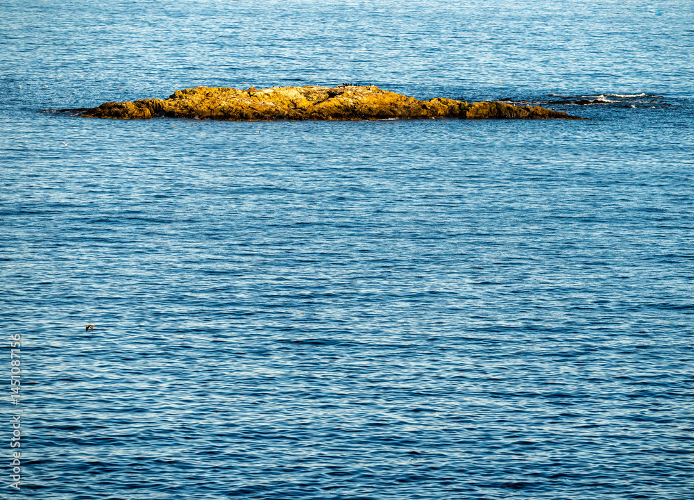 Small Rocky Outcropping Catches Sun Light With Ocean Copy Space