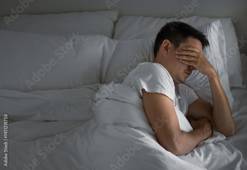 Sleepless man lying in bed feeling tired stressed	