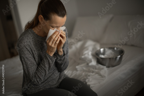 young woman feeling ill blowing nose sneezing with flu symptoms, coughing with mouth covered