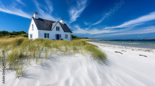 Fototapeta Naklejka Na Ścianę i Meble -  White Coastal Cottage on Sandy Beach Under Blue Sky
