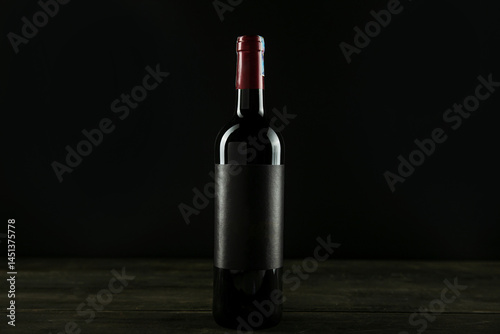 Bottle of red wine. Dark glass bottle with blank label mock up on black backdround