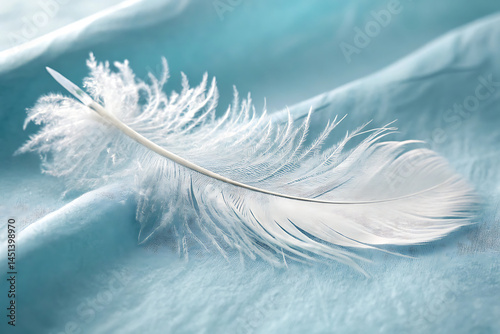 Delicate white feather on soft blue fabric surface in a macro shot.