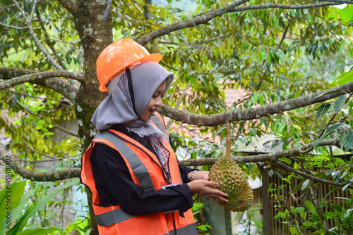 Photos Young Asian woman farmer checking industrial scale durian plantation