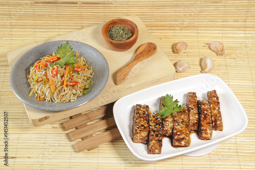 A plate of stir-fried bean sprouts and grilled tempeh. A delicious choice of dishes
