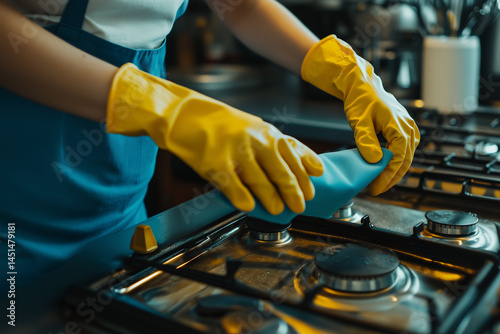 Obraz na płótnie Young woman cleaning kitchen stove with gloves w salonie