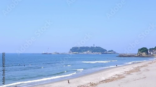 サーファーが波と戯れる夏真っ盛りの湘南・鎌倉の海と、美しい江ノ島の風景で、夏休みのイメージ
