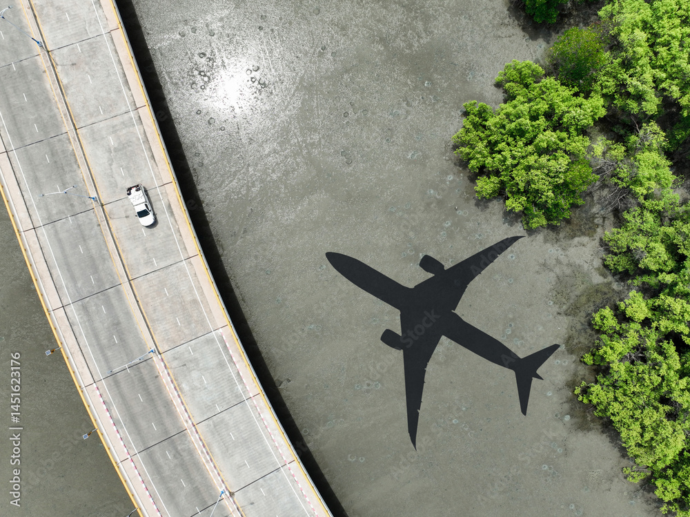 Airplane shadow flying over mangrove forest with car driving on coastal concrete bridge. Sustainable aviation biofuel technology. Environmental conservation. Eco-friendly flight. Mangroves capture CO2