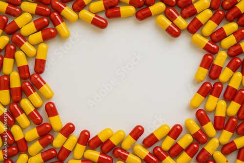AI generated pharmaceutical image featuring vibrant red and yellow capsules arranged in perfect circular formation with clean white negative space at center, ideal for medication healthcare visuals