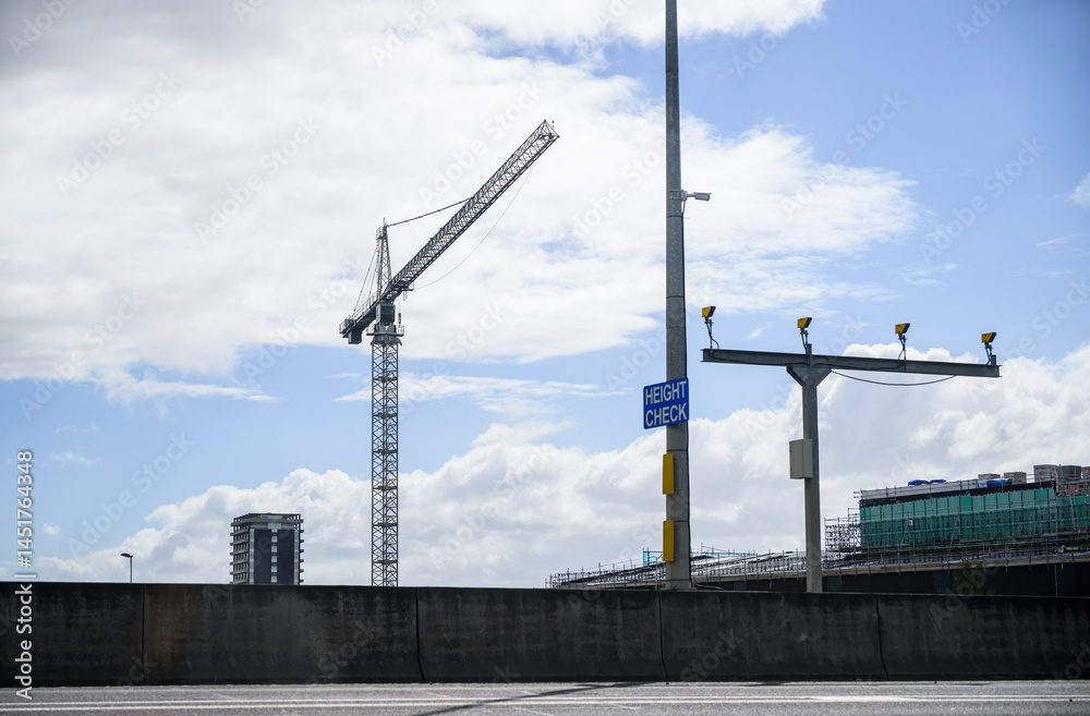 Construction crane above the building under construction. HEIGHT CHECK sign on the post. Auckland.