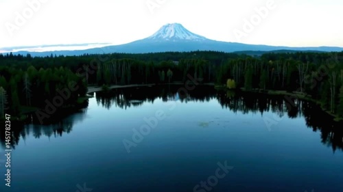 Aerial The surface of a calm lake in the forest reflecting the beautiful Mount Hood in the background.