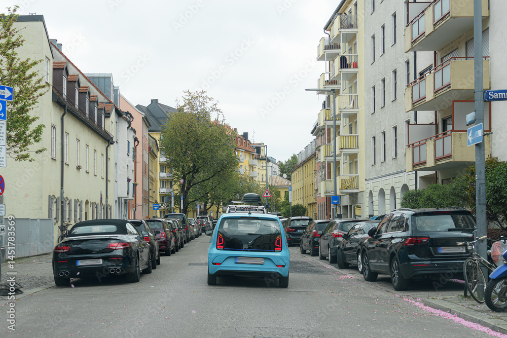 Obraz premium Busy residential street with parked cars and apartment buildings on an overcast day in a city