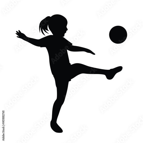 Silhouette of a young girl playing soccer, kicking the ball