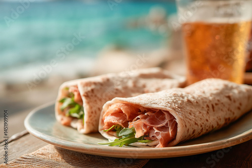 Deliziose piadine arrotolate con il prosciutto crudo e un bicchiere di birra sul tavolo vicino al mare
