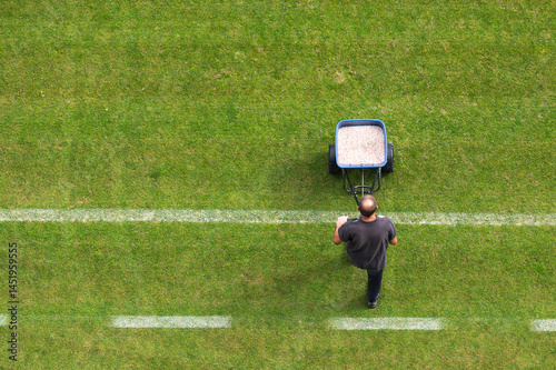 Obraz na płótnie Groundsman spreads fertilizer for grass on a football pitch w salonie