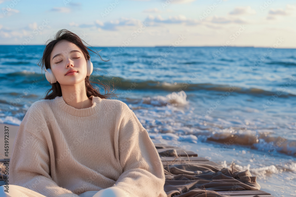 Fototapeta premium Young woman listening music with headphones on beach at sunset, enjoying relaxing sounds