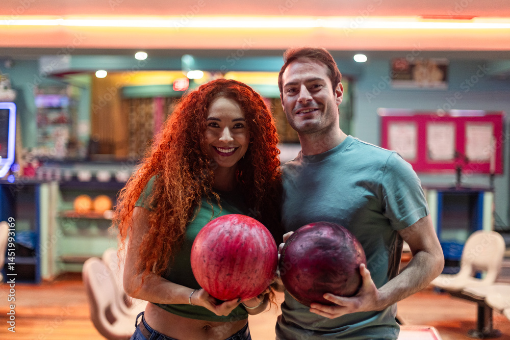 Fototapeta premium Happy couple holding bowling balls in bowling alley