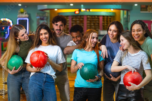 Group of young people having fun, holding bowling balls, ready to play