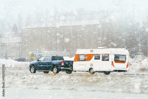 Pickup truck towing camper in winter landscape
