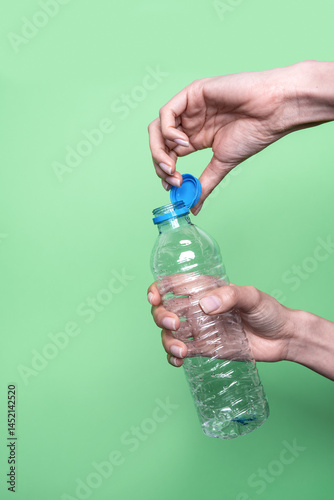 Opening a plastic water bottle against green background