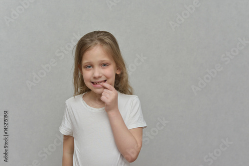 A girl with blond hair points to a fallen tooth. Dental health concept. Dentistry