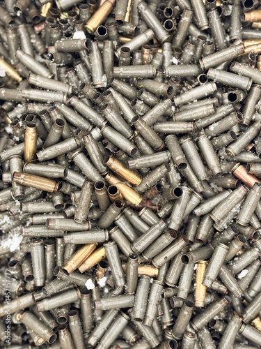 Wet, snowy, empty cartridge cases for a machinegun, carbine or rifle. Background of shiny cartridges to illustrate armed conflict, war or shooting events. Military background.
