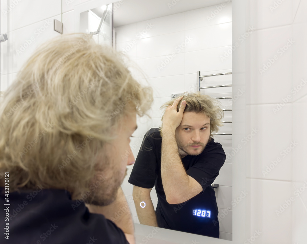 morning routine, young man looking in mirror in bathroom morning routine, young man looking in mirror in bathroom