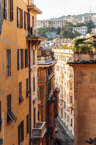 Fototapeta Naklejka Na Ścianę i Meble -  Genoa, Italy - September 22, 2024: Colorful hillside buildings and narrow streets climb toward the Castelletto district, offering panoramic views over the city and port.