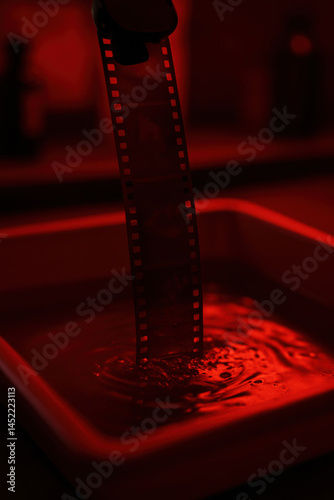 Moody analog film strip developing under red darkroom light