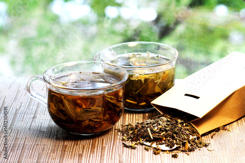 Two glass cups of herbal green tea and a pack of dry tea.