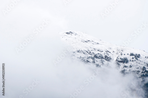 Snow-covered mountain slope emerging from fog