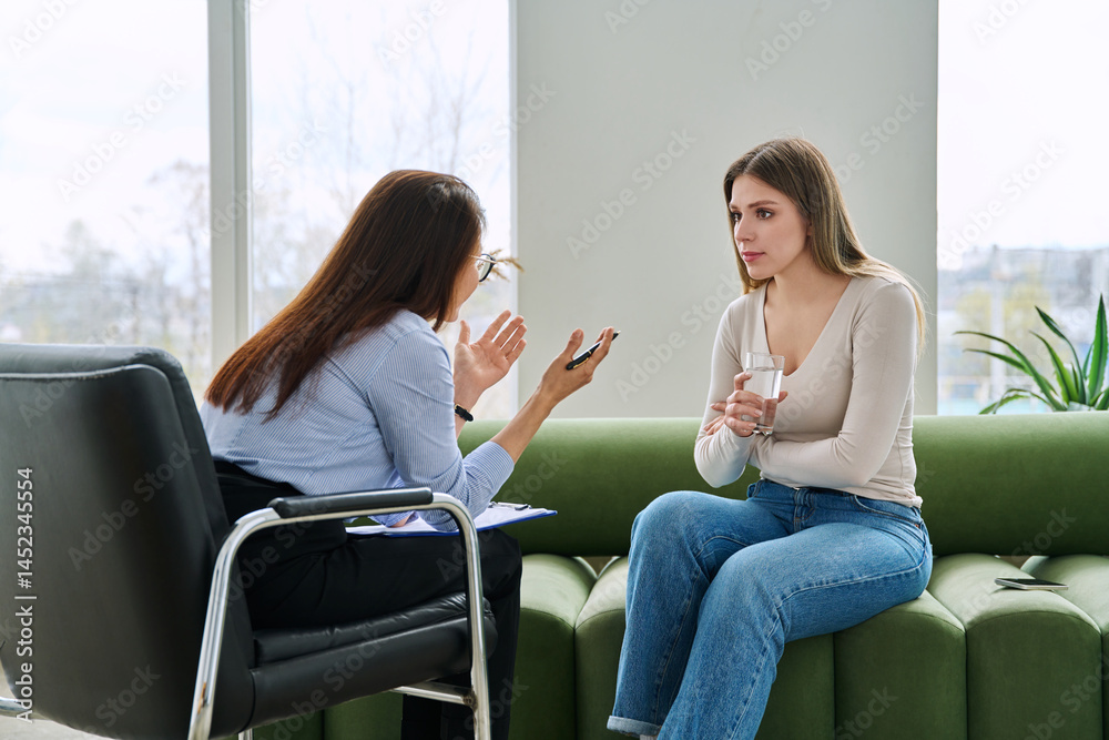 Young woman in mental session talking to female psychologist, therapist