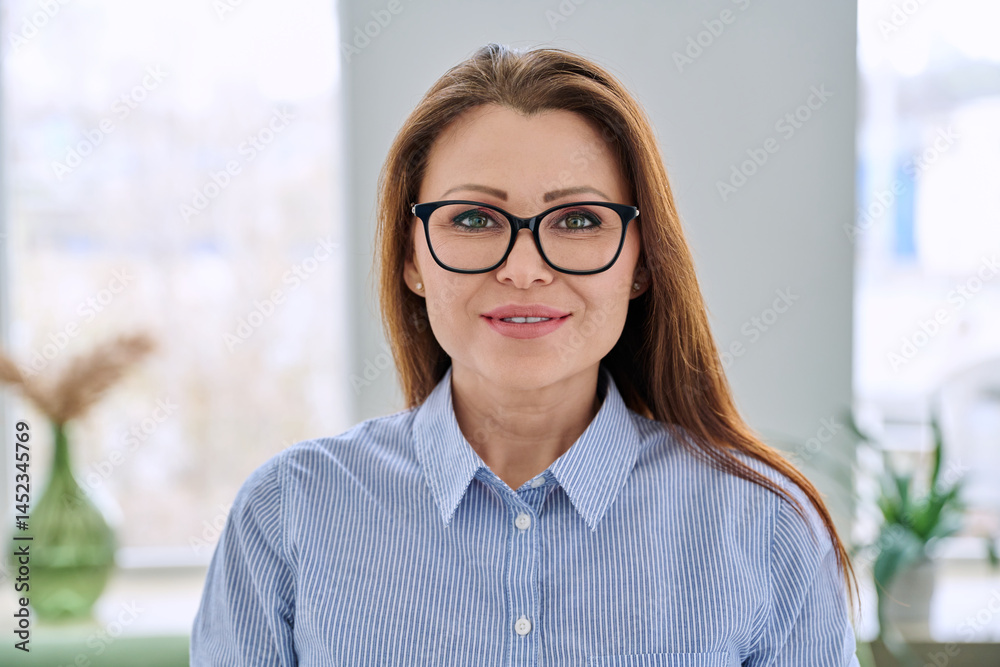 Headshot portrait of smiling businesswoman with glasses in blue shirt