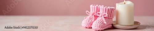 Pink knitted booties and a white christening candle , faith, religious symbol, God