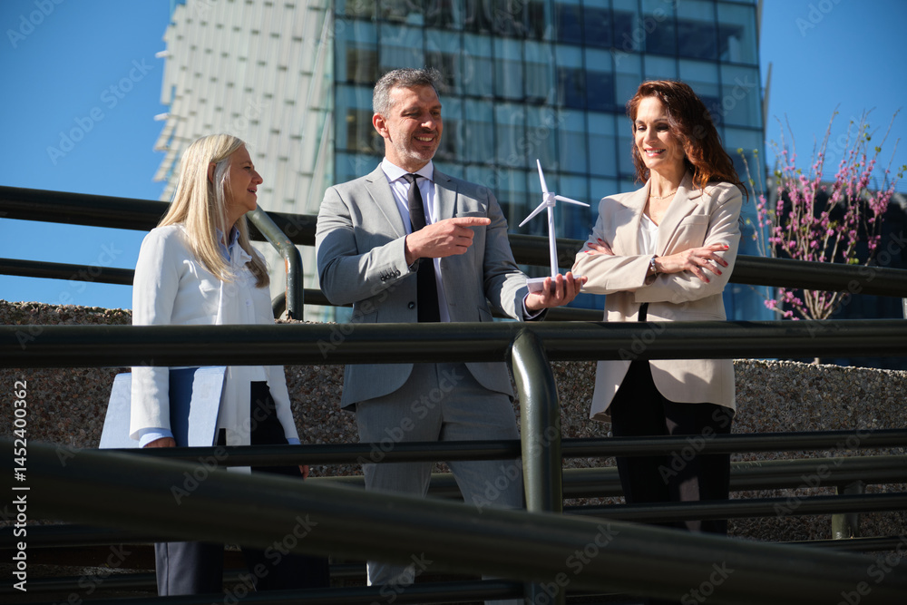 Business team discussing renewable energy project with miniature wind turbine